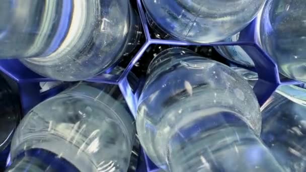 Close-up van glazen flessen gevuld met mineraalwater in blauwe plastic verdelers.  - Video