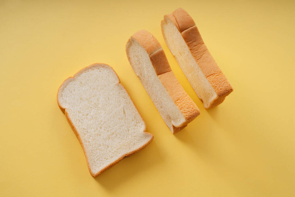 Σπιτικό βιολογικό ψωμί κομμένο σε φέτες πάνω από κίτρινο φόντο. - Φωτογραφία, εικόνα