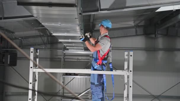 新規工事現場の天井に新設された空気ベントの一部を締め付ける男性請負業者の閉鎖. - 映像、動画