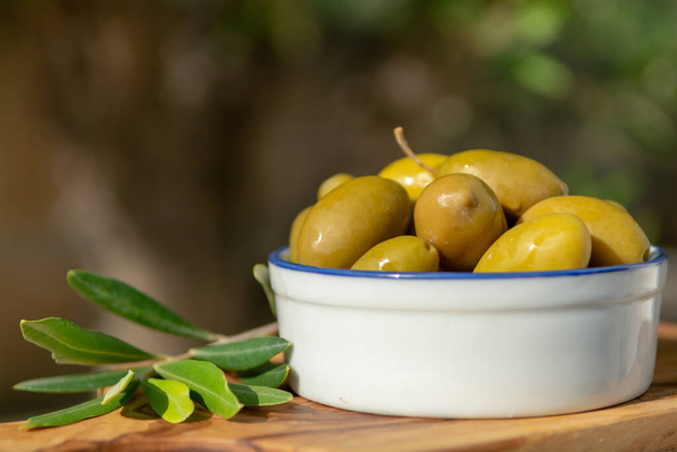 Ciotola con olive verdi servita come spuntino all'aperto nel giardino degli ulivi
 - Foto, immagini