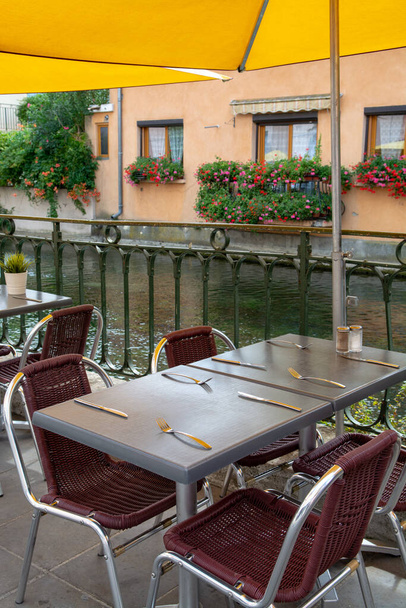 Vazio acolhedor café de rua francês ou brasserie localizado no pequeno rio com mesas servidas pronto para os visitantes, férias de verão
 - Foto, Imagem