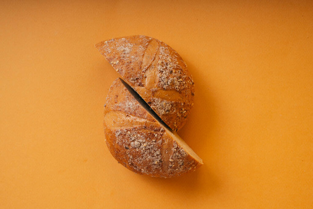 Dva krajíce bochníku chleba na oranžovém pozadí. Horní pohled. - Fotografie, Obrázek