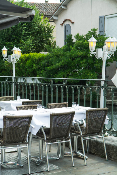 Vacío acogedor café de la calle francesa o brasserie situado en el pequeño río con mesas servidas listas para los visitantes, vacaciones de verano
 - Foto, imagen