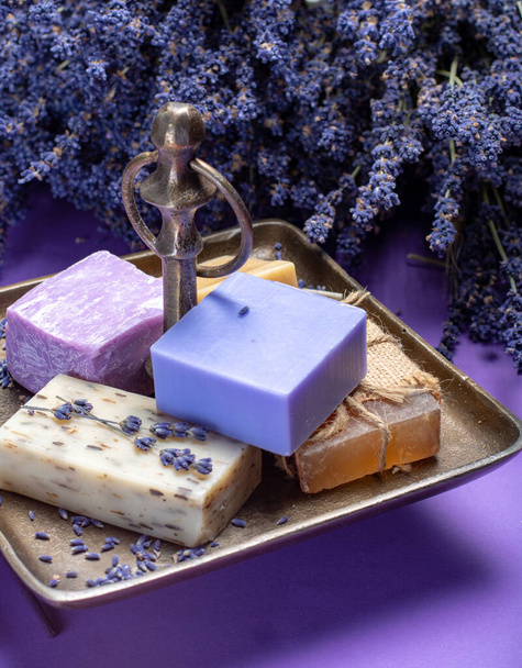 Naturalna, zdrowa aromaterapia i pielęgnacja skóry organiczną francuską lawendą, mydło lawendowe na fioletowym tle z suszonymi kwiatami lawendy z bliska - Zdjęcie, obraz