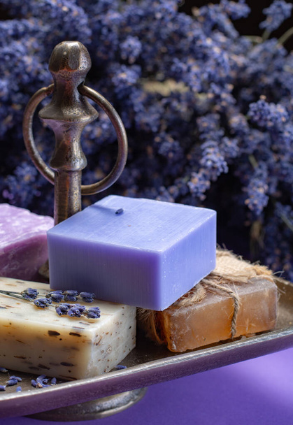 Přírodní zdravá aromaterapie a ošetření pleti s organickou francouzskou levandulí, levandulové mýdlo na purpurovém pozadí se sušenými květy levandule zblízka - Fotografie, Obrázek