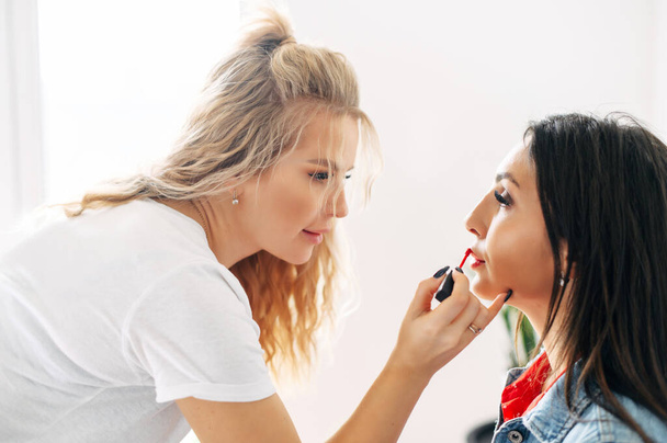One girl put lipstick on lips of another girl - Fotó, kép