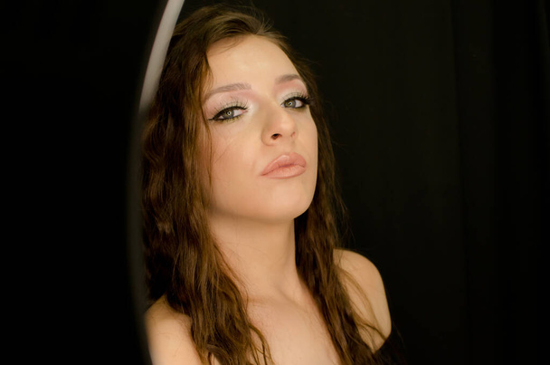 retrato de bela jovem morena em estúdio com profissional compõem em fundo preto, ombros nus com cabelo sobre, expressão sensual imagem vertical
 - Foto, Imagem