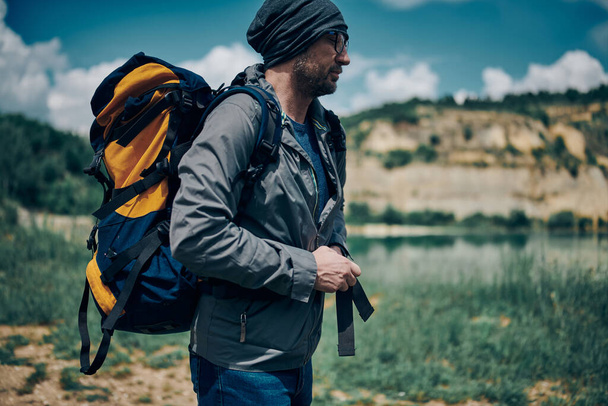 Junger gutaussehender Mann mit Rucksack auf dem Rücken in der Natur stehend. Konzept Camping am Wochenende. - Foto, Bild