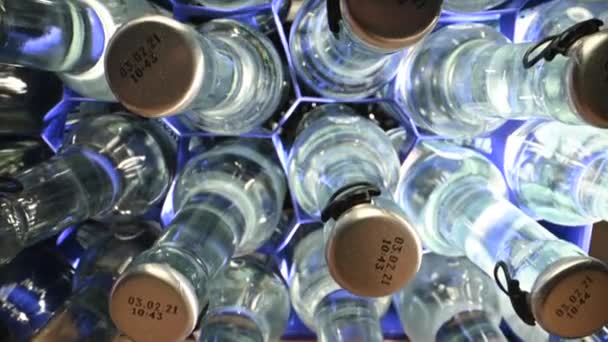 Bovenaanzicht van glazen flessen en metalen doppen met mineraalwater geplaatst in blauwe plastic containers.  - Video