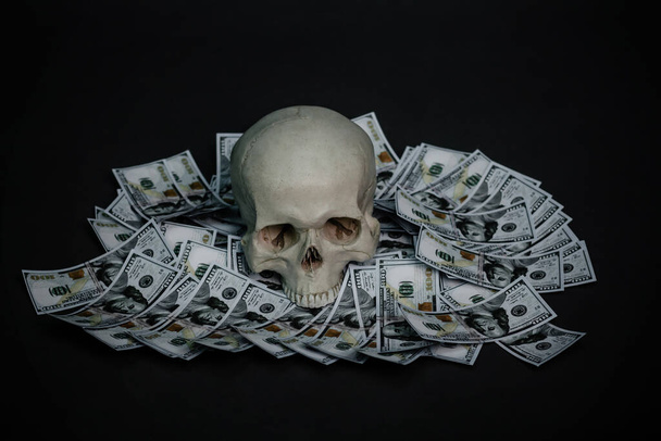 Een menselijke schedel ligt in het donker op geld.. - Foto, afbeelding