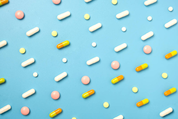 Крупный план многих различных таблеток, расположенных в шаблоне на синем фоне. - Фото, изображение
