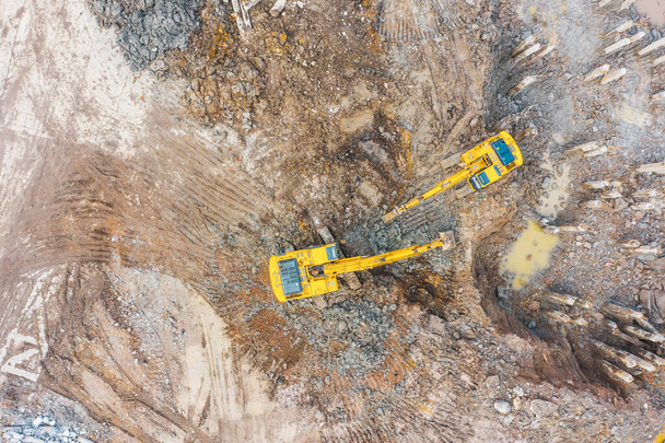 La excavadora cava arcilla desde el pozo de cimentación del edificio, las pilas restantes, vista aérea superior
 - Foto, Imagen