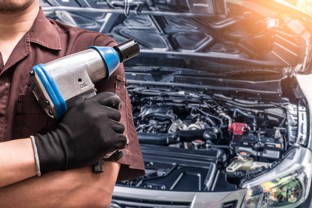 technician hold a air wrench and blurred disc brake is backdrop. the concept of automotive, repairing, mechanical, vehicle and technology - Valokuva, kuva