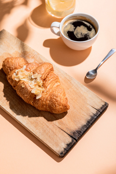 fresh croissants on wooden board and cup of coffee for breakfast on beige table  - Фото, зображення