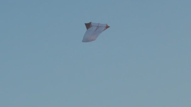 Vzdušný bílý drak létající v modré bezmračné obloze kopíruje textový prostor. Nízký úhel pohledu na beztížnou hračku vznášející se ve zpomaleném pohybu vzduchu. Nezávislost na svobodě. Letní symbol štěstí - Záběry, video