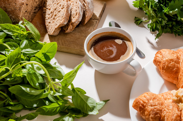 bread, croissants, greenery and cup of coffee for breakfast on grey table  - Φωτογραφία, εικόνα