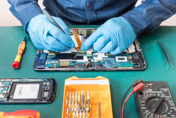 The abstract image of the technician repairing inside of tablet by screwdriver in the lab. the concept of computer hardware, mobile phone, electronic, repairing, upgrade and technology. - Photo, Image