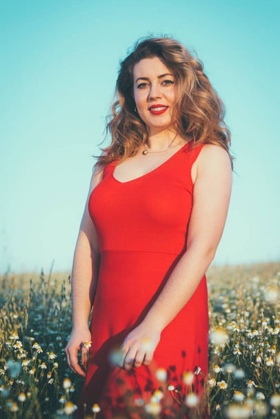 woman in red dress enjoying freedom in a field of daisies - Fotografie, Obrázek