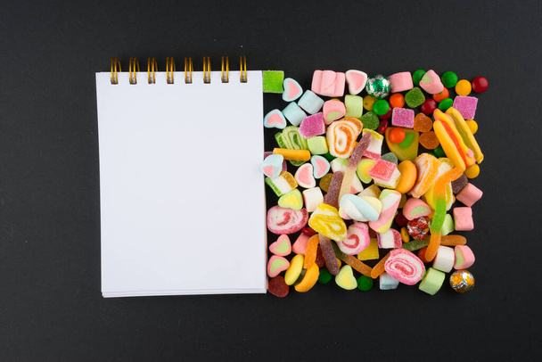 Creative arrangement of colorful candies and sweets on dark background. Flat lay view. - Фото, зображення