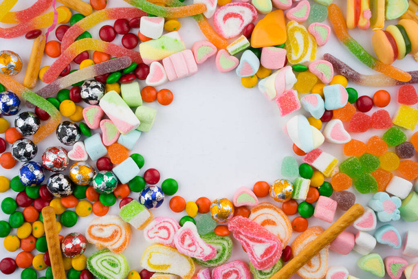 Kreatív elrendezése színes cukorkák és édességek fehér háttérrel. Lapos kilátás. - Fotó, kép