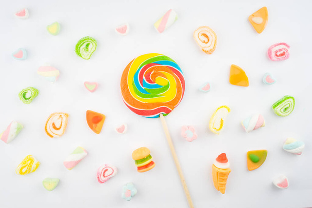 Disposizione creativa di caramelle colorate e dolci su sfondo bianco. Vista lastra piatta
. - Foto, immagini