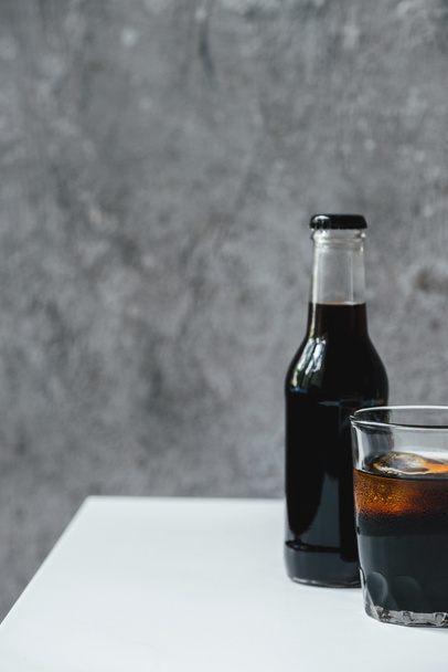 café froid infusé avec glace en verre et bouteille sur table blanche
 - Photo, image