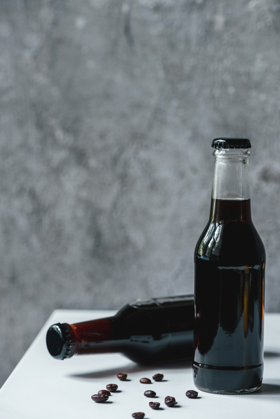 cold brew coffee in bottles near coffee beans on white table - Photo, Image