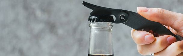 vista cortada da mulher abrindo café frio brew em garrafa com abridor, tiro panorâmico
 - Foto, Imagem