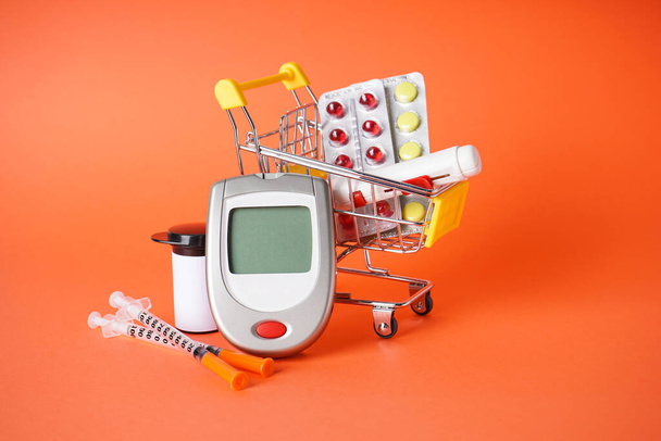 Diyabet konsepti. Şeker hastası alışveriş arabası, aksesuarlar, dijital glukometre ve kırmızı bir sırt çantasına şırınga.. - Fotoğraf, Görsel