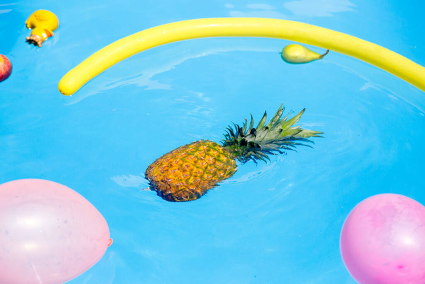 Різні фрукти, іграшки та повітряні кулі, що плавають у воді басейну
 - Фото, зображення
