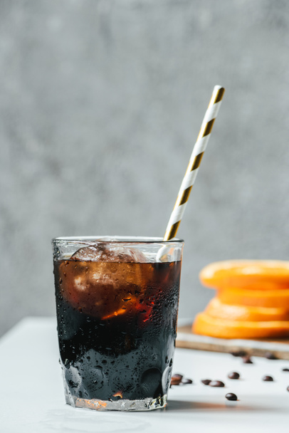 selective focus of cold brew coffee with ice and drinking straw on white table - Photo, Image