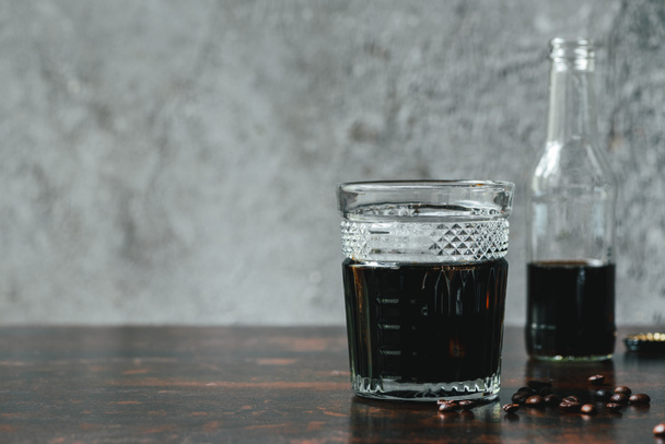 selective focus of cold brew coffee in bottle and glass near coffee beans - Zdjęcie, obraz