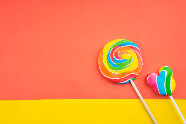 Concepto caramelos y dulces. Piruletas de colores sobre fondo de colores vibrantes
 - Foto, imagen