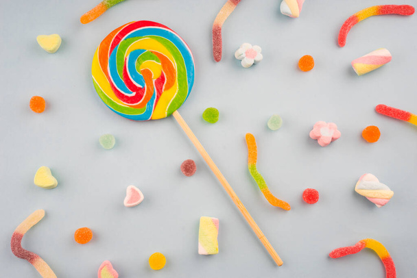 Renkli şekerlerin ve pastel arka planda tatlıların yaratıcı düzenlemesi. Düz görünüm. - Fotoğraf, Görsel