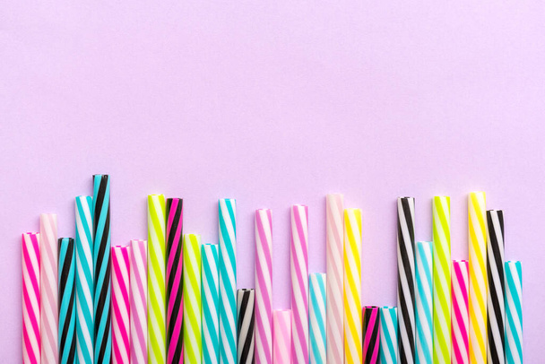 drinking straws with stripes for party on lilac background. Top view of colorful plastic tubes for summer cocktails. Flat lay Copy space Birthday, party, creative, art concept. - Photo, Image