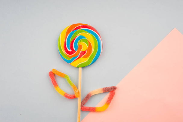 Renkli şekerlerin ve pastel arka planda tatlıların yaratıcı düzenlemesi. Düz görünüm. - Fotoğraf, Görsel