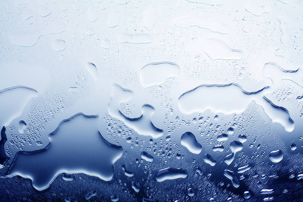 Влажная стеклянная поверхность в каплях воды, синий градиент, иллюстрация прохладной или холодной воды, текстура пролитой воды, абстрактный фон, компоновка, баннер, обои, капли конденсата на стекле крупным планом
 - Фото, изображение