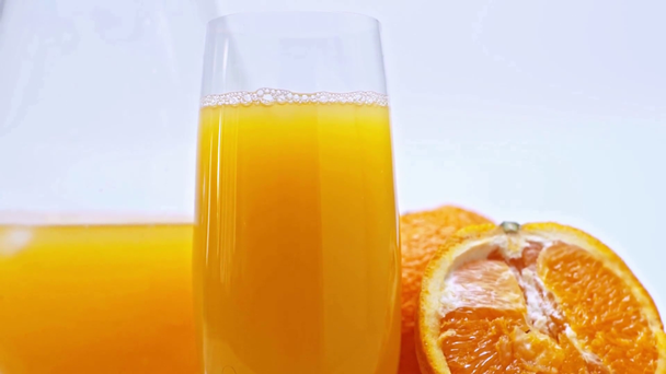 Vaso de zumo de naranja y naranjas sobre superficie de madera aislada sobre blanco
 - Metraje, vídeo