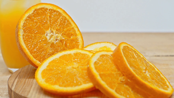 Jugo de naranja y naranja en rodajas sobre superficie de madera aislada sobre blanco
 - Metraje, vídeo