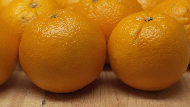 Close up widok świeżych pomarańczy na drewnianej powierzchni izolowane na pomarańczowy - Materiał filmowy, wideo