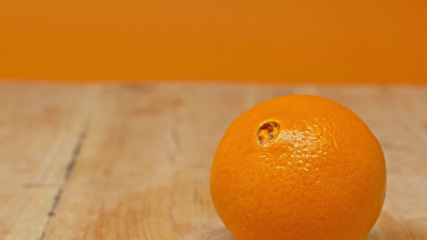 Fresh orange rolling on wooden surface isolated on orange - Footage, Video