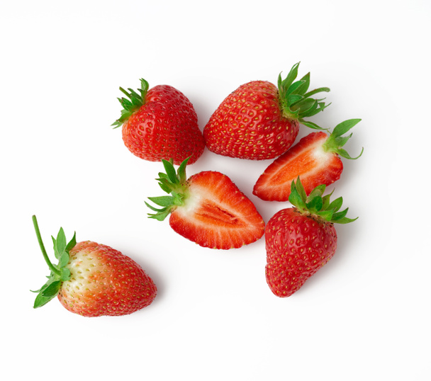 whole and halves of fresh ripe red strawberries with green ponytails on a white background, too view - 写真・画像