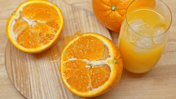 Vista de alto ángulo del jugo de naranja y naranjas en la superficie de madera
 - Imágenes, Vídeo