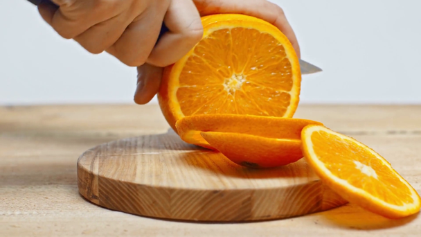 Cropped view of man cutting orange on wooden surface isolated on white - Footage, Video