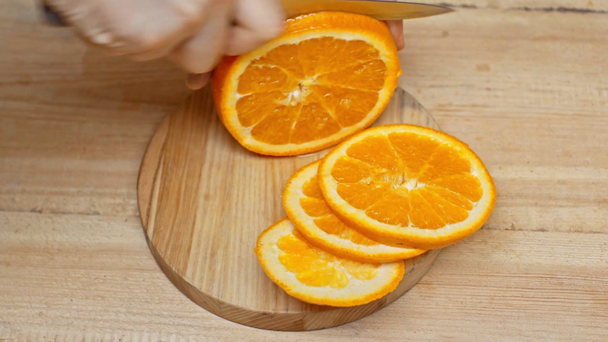 Hochwinkelaufnahme des Mannes, der Orange auf Holzoberfläche schneidet - Filmmaterial, Video