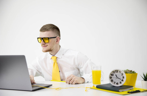 Giovane uomo caucasico impiegato con una cravatta gialla lavora al suo computer portatile
. - Foto, immagini