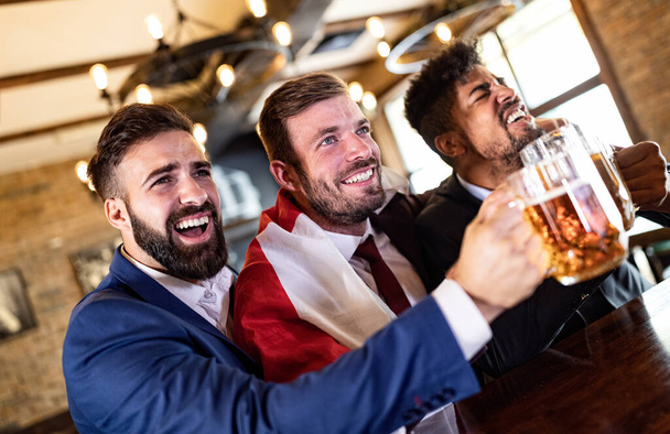 Business men fans screaming and watching football on TV and drink beer in a pub - Foto, Bild