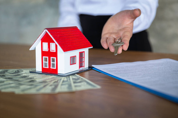 Czerwony dach umieszczony na banknotach Agent posiada klucz do koncepcji Klienci, którzy kupują produkty lub podpisują umowy, koncepcji kupna i sprzedaży domów, kredytów hipotecznych, nieruchomości. - Zdjęcie, obraz