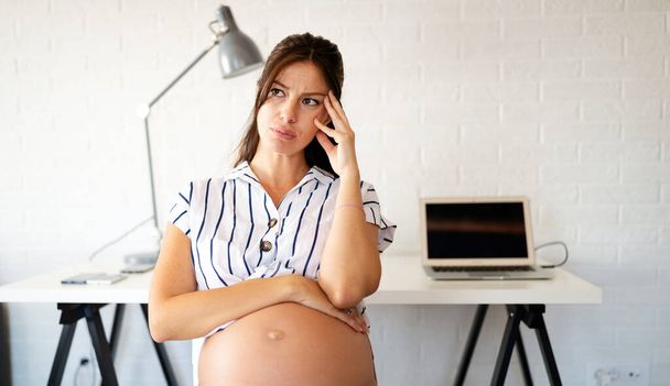 Young pregnant woman working from home. Career and pregnancy concept - Valokuva, kuva