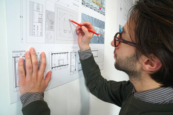 Młody architekt z notatkami na ubraniu w planie budowy - Zdjęcie, obraz
